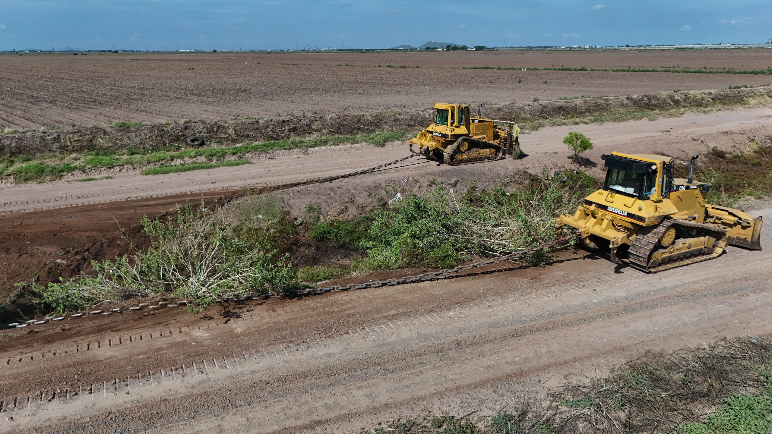 Dos bulldozers realizando trabajos de conservación sobre el bordo de un canal.